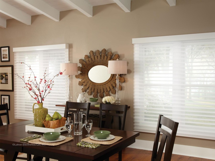 A well-lit dining room with fully lowered motorized blinds on the windows.