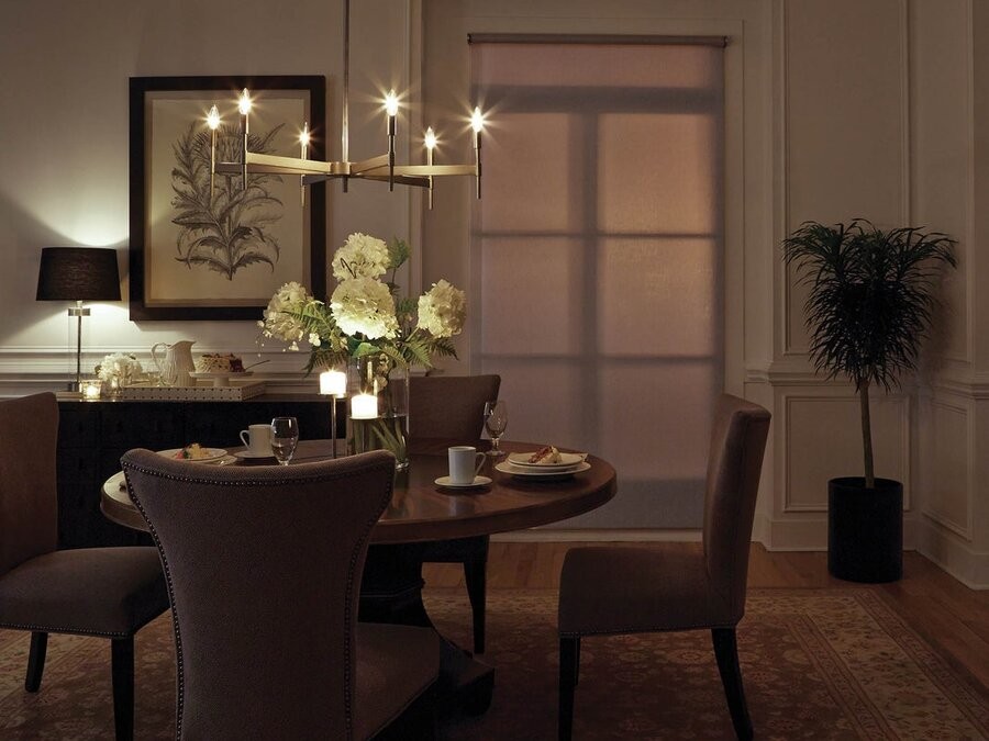 A dining room featuring a table and seats, lowered shading, and tunable lighting fixtures.