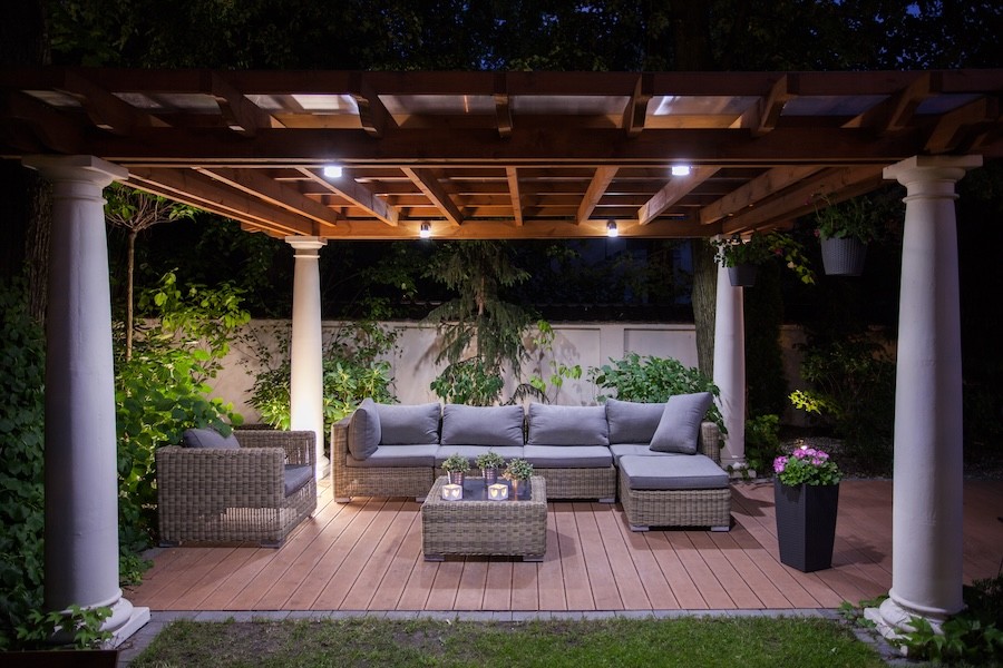 An outdoor pergola with comfortable furnishings and relaxing light.