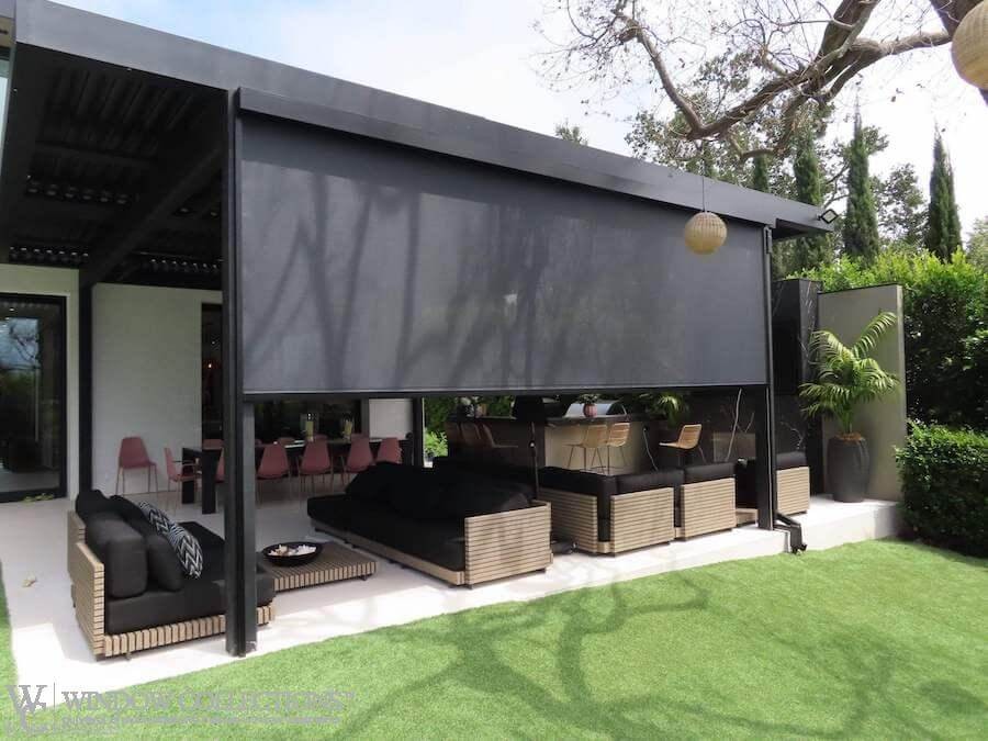 Image is of a motorized exterior shade covering an outdoor patio with multi-couch seating.