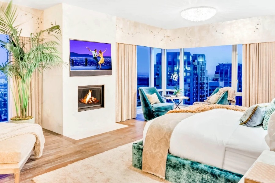  Inviting bedroom with a fireplace, stylish draperies, and a breathtaking view of the city. 