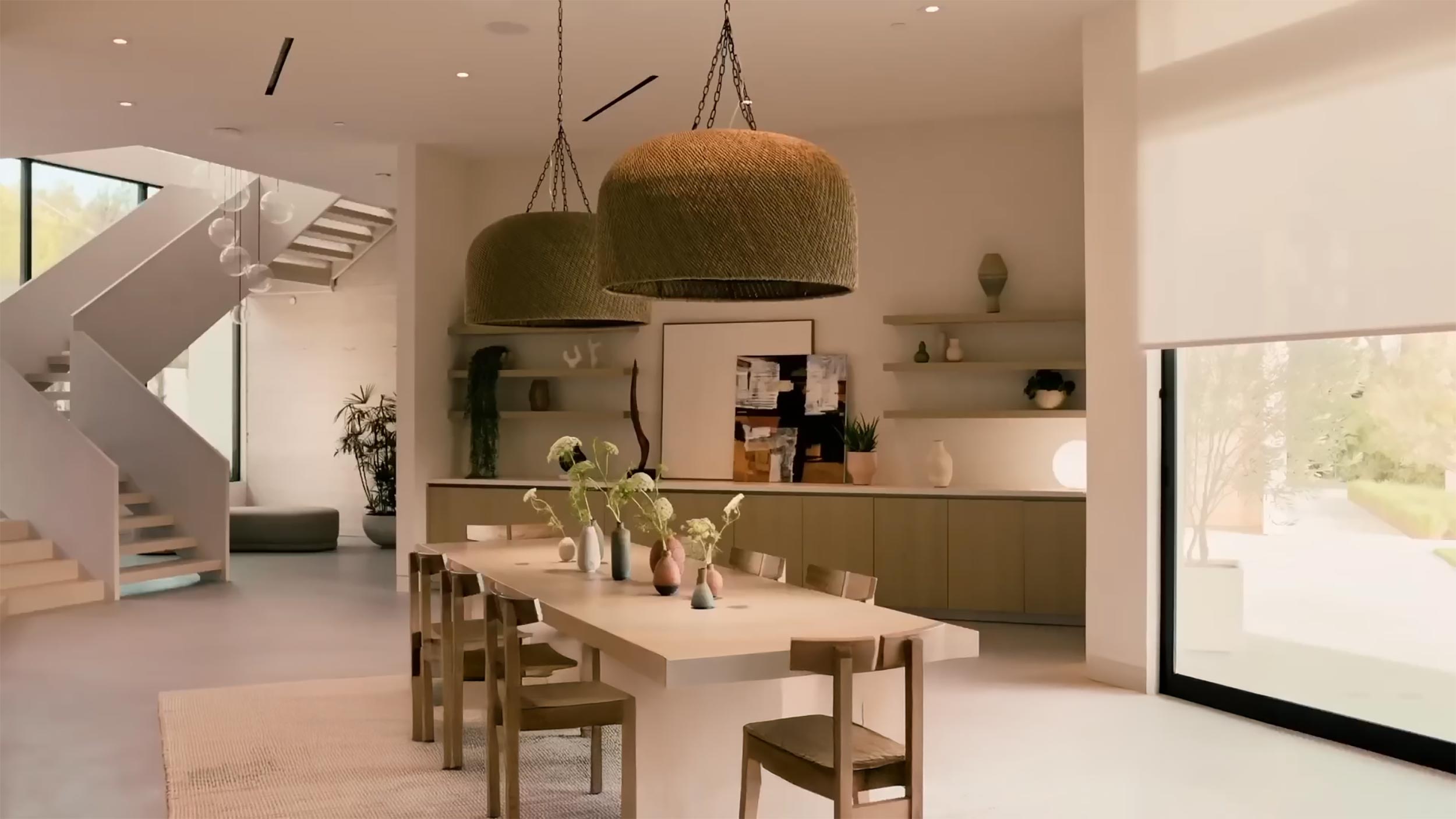 Modern dining area with wooden table, six chairs, and large woven pendant lights in a minimalist home interior